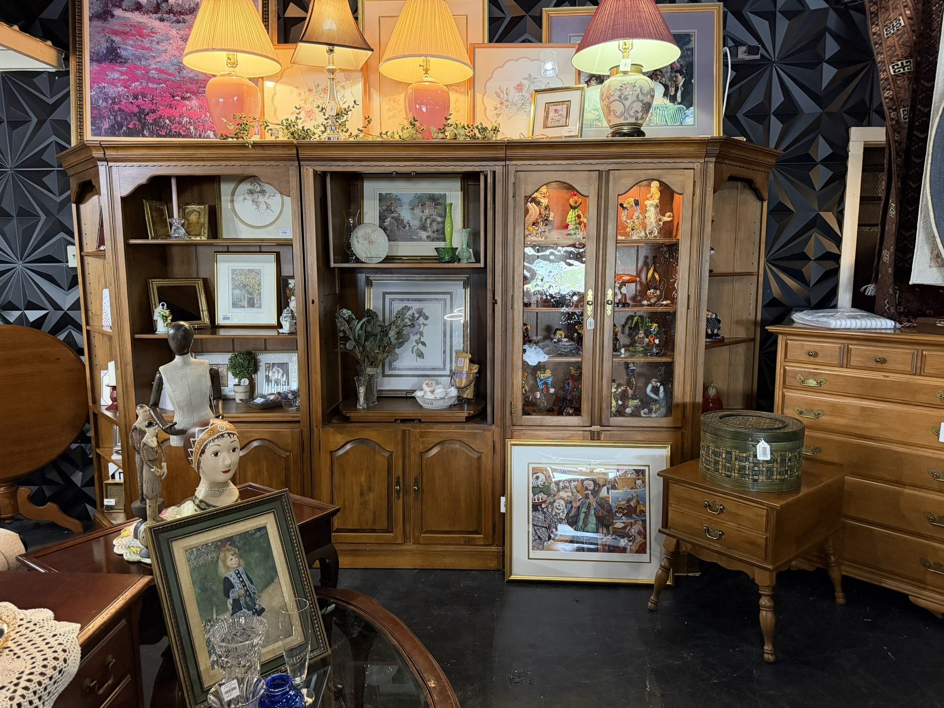 Antique wooden cabinet with framed art and lamps in a cozy vintage shop display