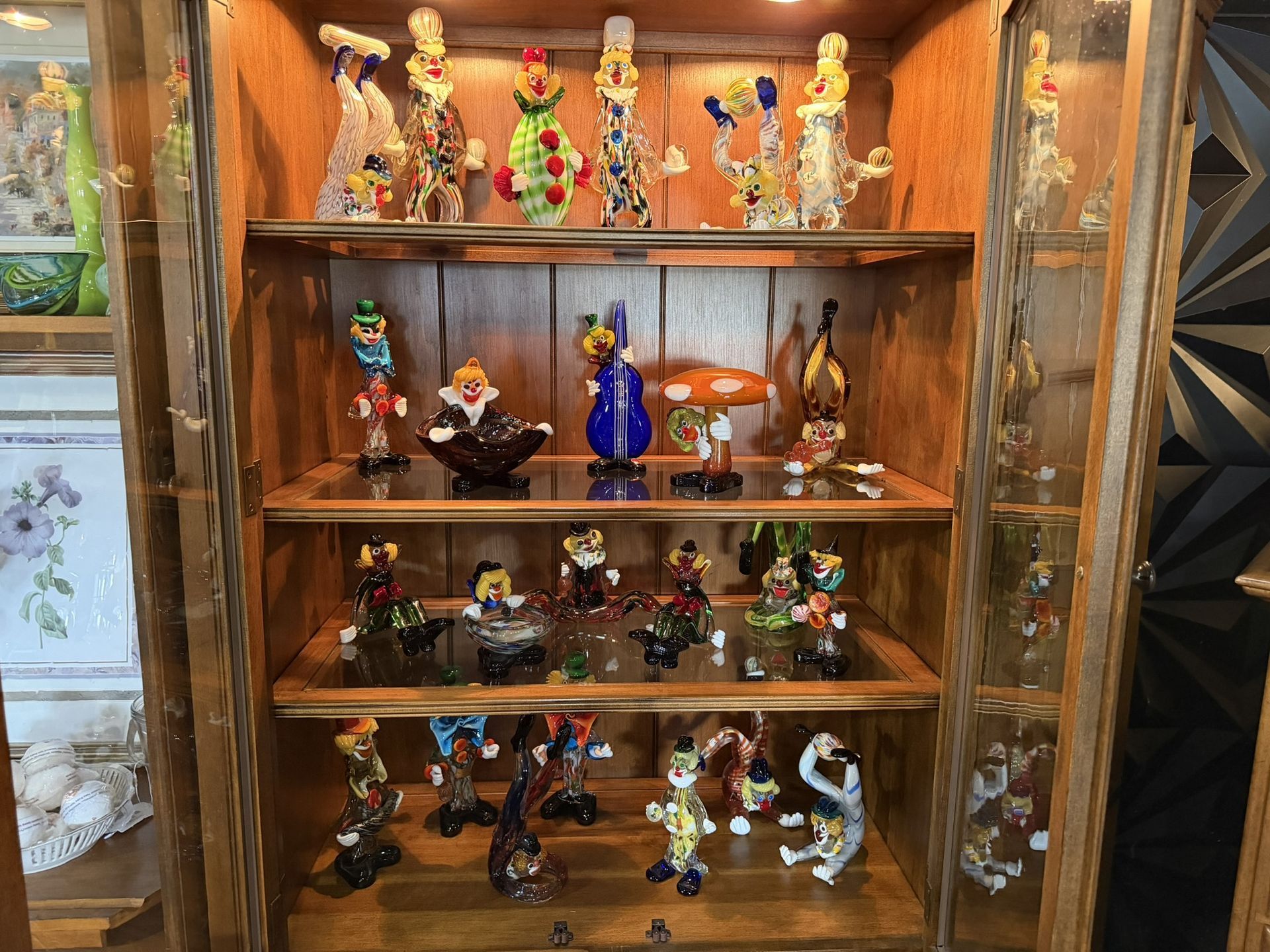 Wooden display cabinet filled with colorful figurines and dolls on multiple shelves