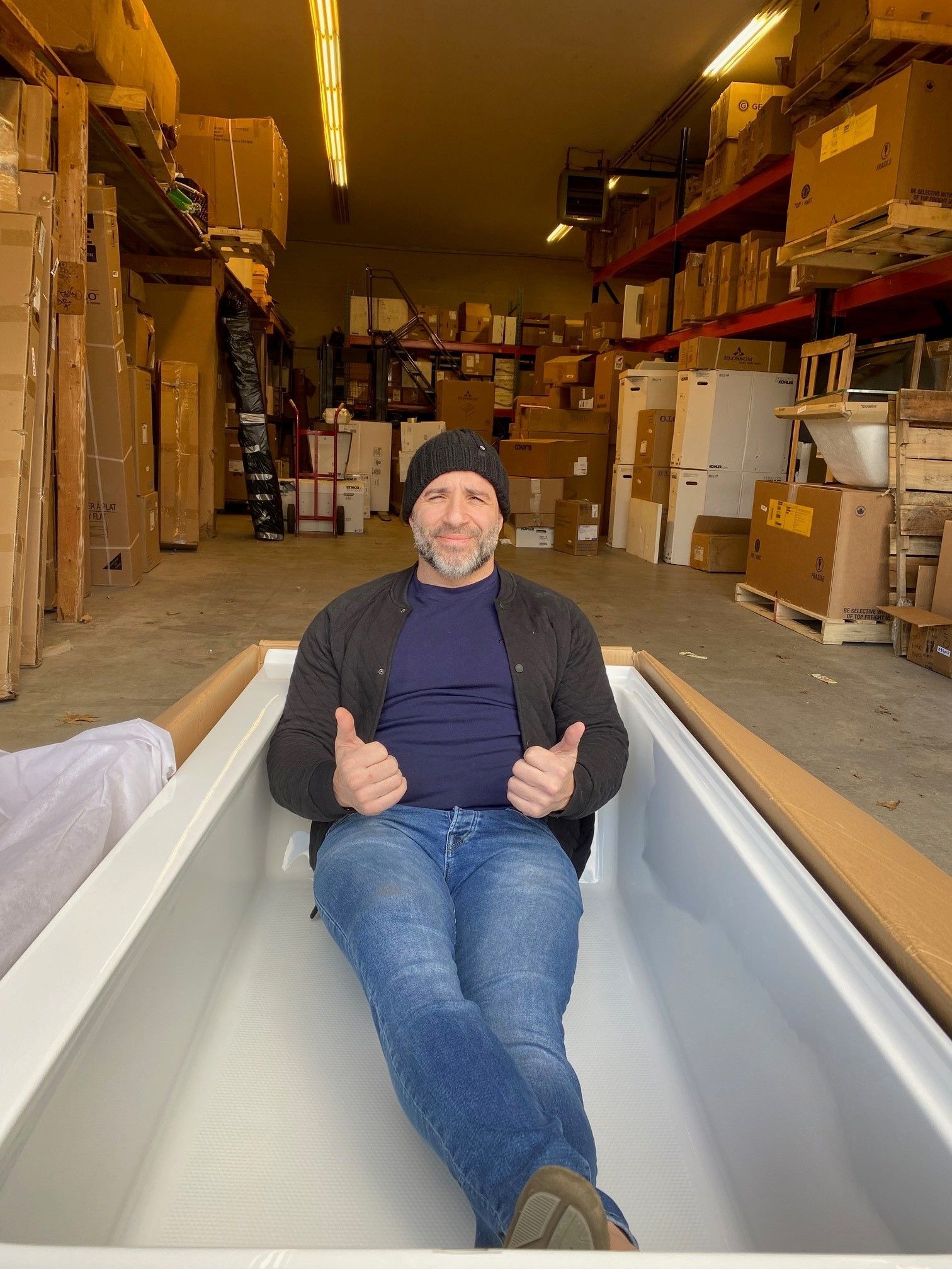 a man is sitting in a bathtub in a warehouse giving a thumbs up