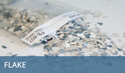 White and blue flakes scattered around a torn label on a light surface, with “FLAKE” at bottom left