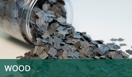 Spilled wood chips from a tipped glass jar with a green “WOOD” label