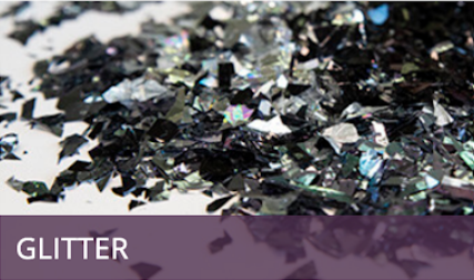 Black glitter flakes on a white surface with a purple “GLITTER” label