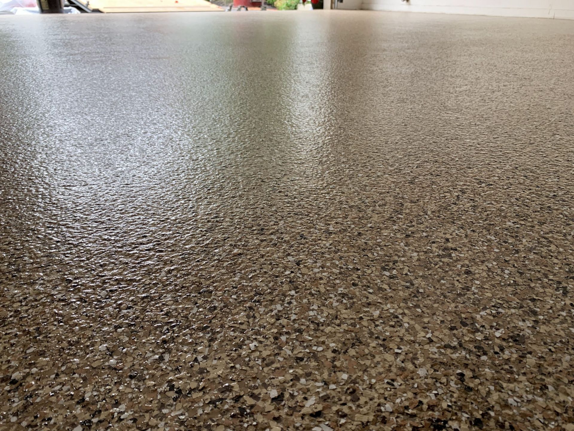 Close-up of a speckled brown textured floor with a bright blurred background