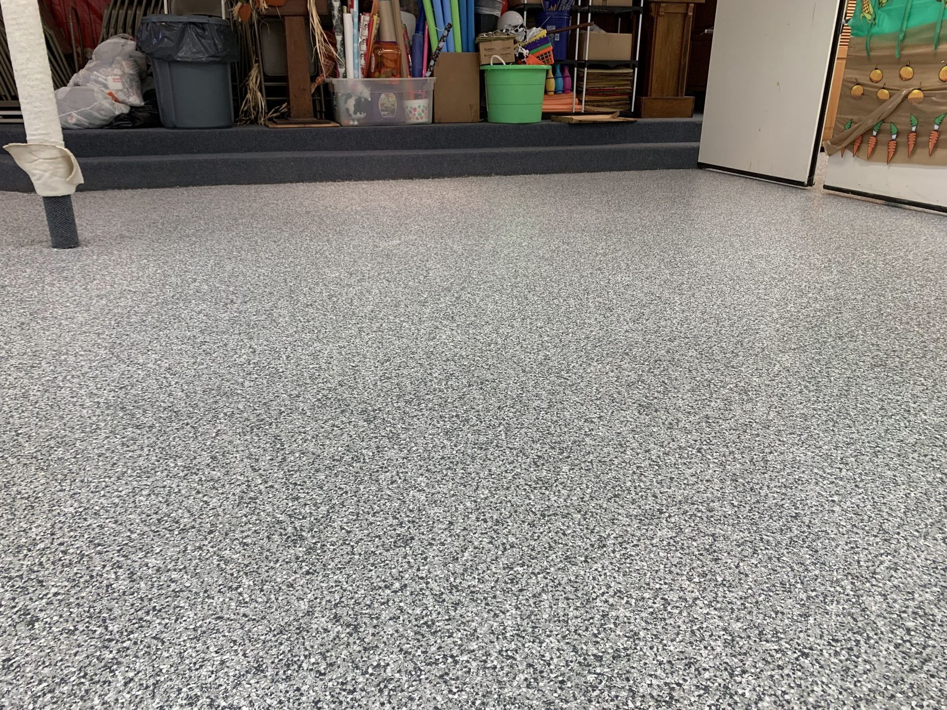 Speckled gray carpet leading to a shop entrance with shelves and colorful containers inside