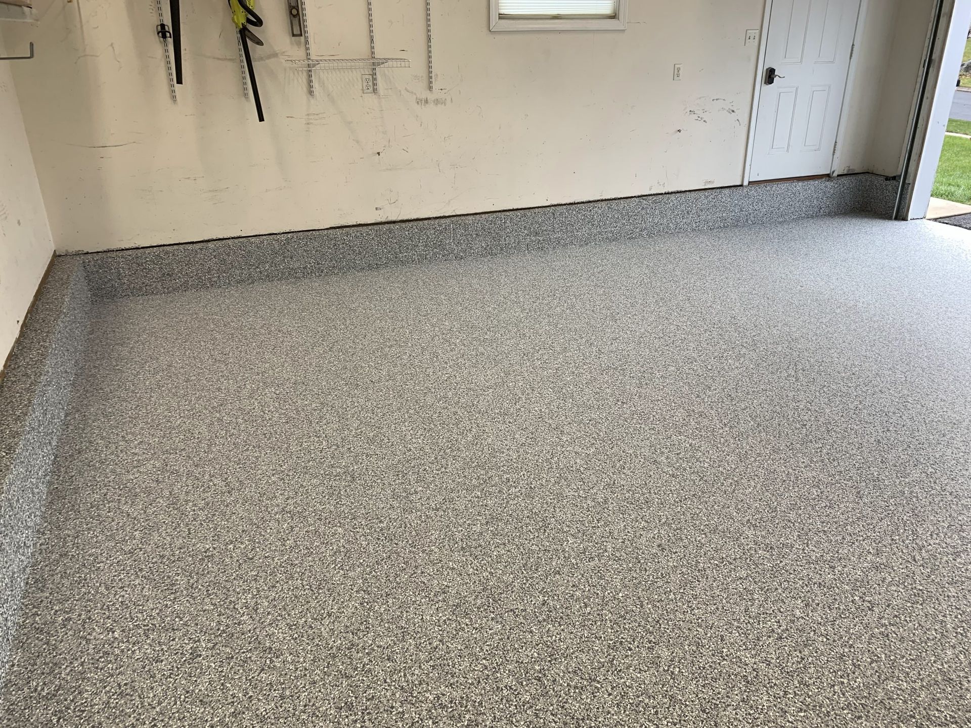 Empty garage with speckled epoxy floor and white walls