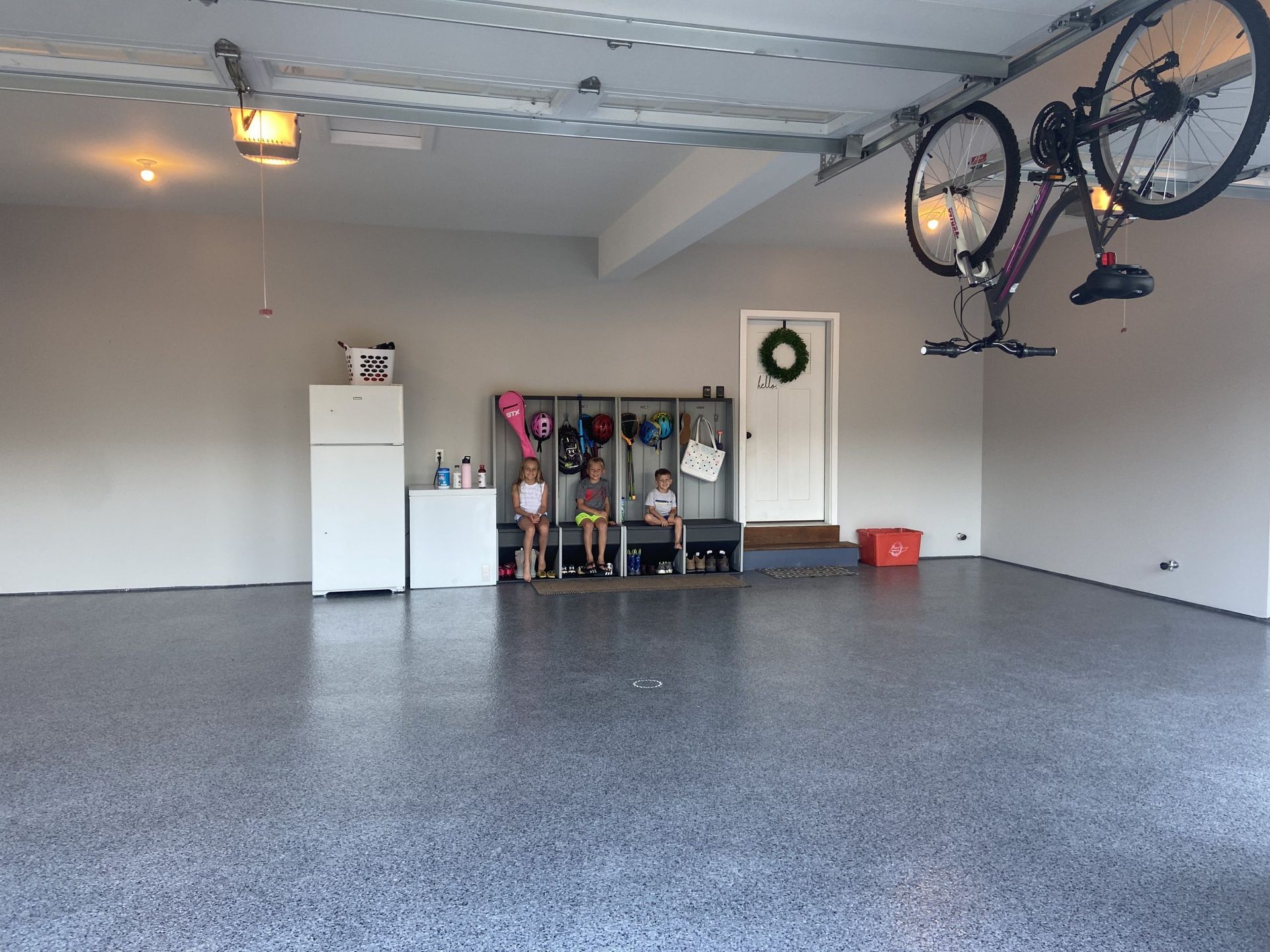 Empty garage with epoxy floor, storage shelves, and a bicycle hanging from the ceiling.