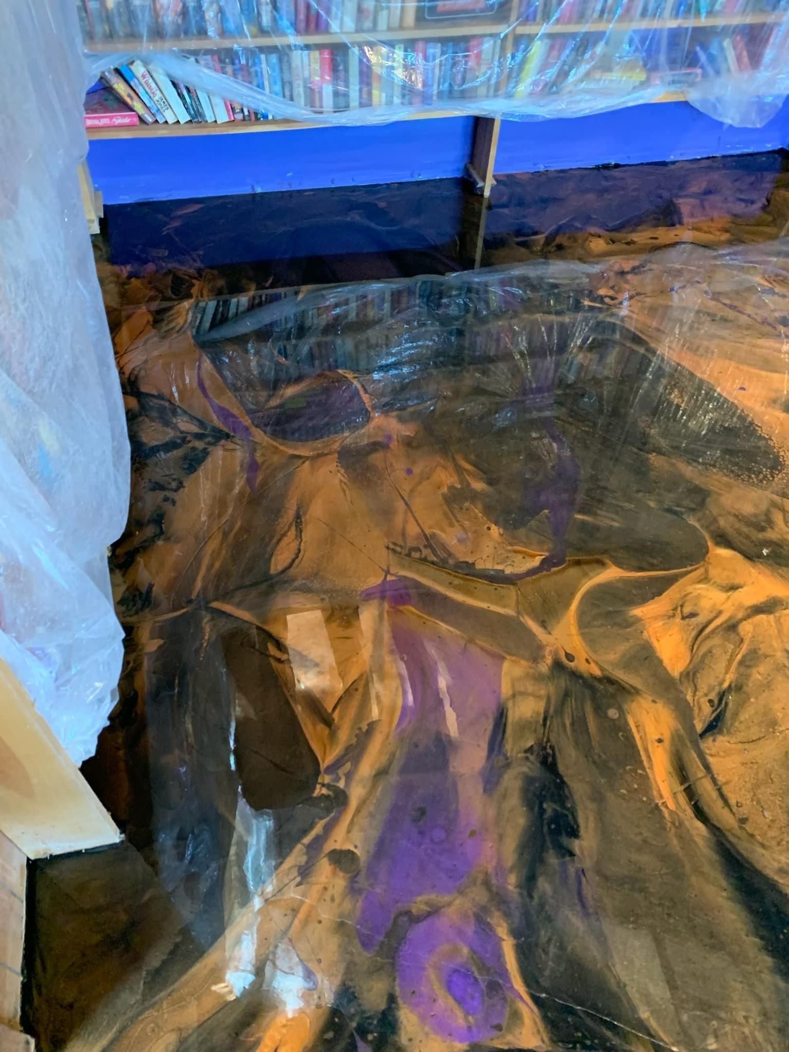Tent, reflective tarp floor, and colorful hanging canopy with a dark scenic backdrop