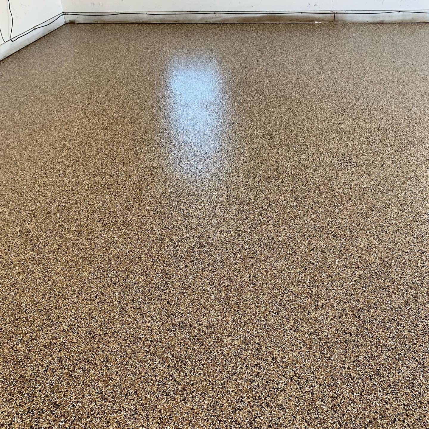 Speckled beige floor with a bright reflection of light near the center