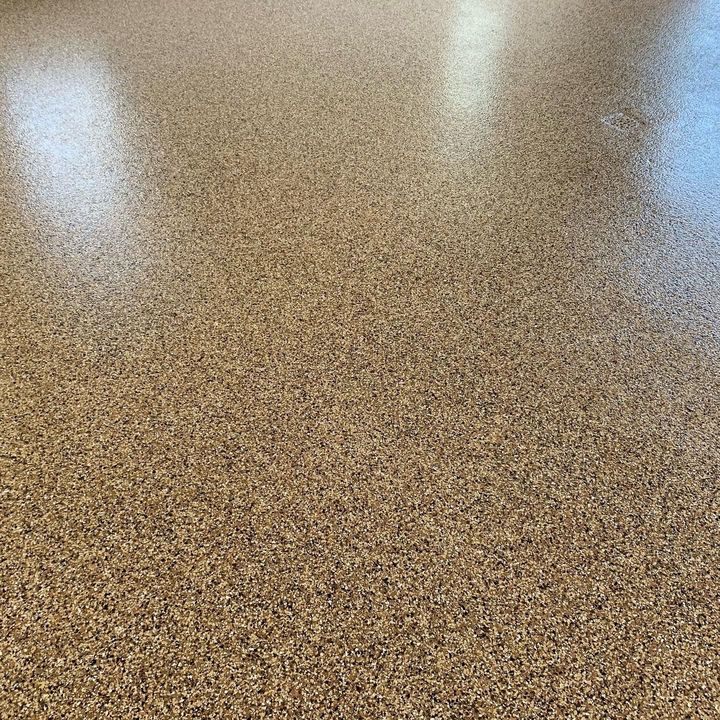 Speckled tan terrazzo floor with soft reflections of overhead lights