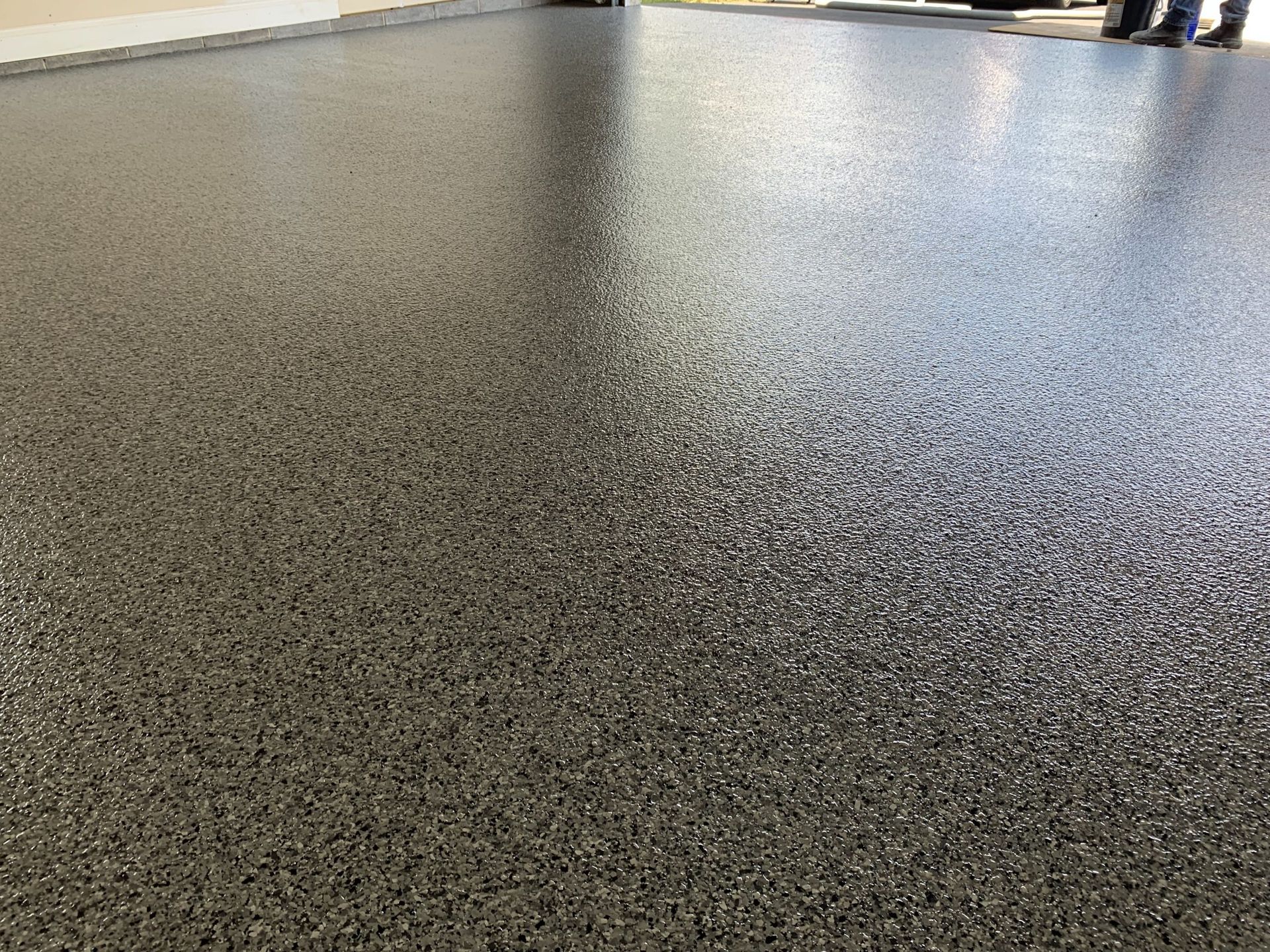Speckled gray floor surface with a blurred background and people standing at the top edge
