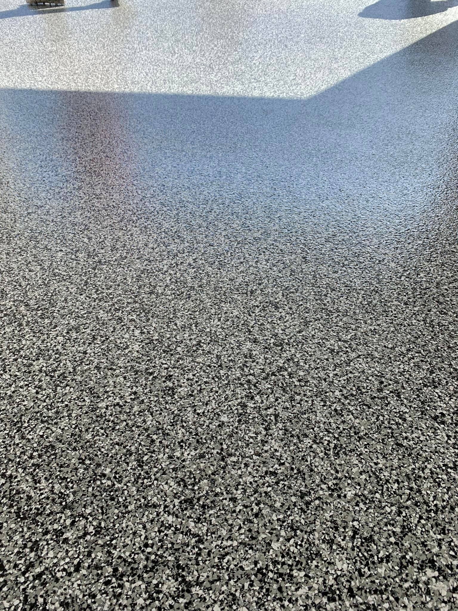 Speckled black-and-white textured floor with bright sunlight and shadows near the top
