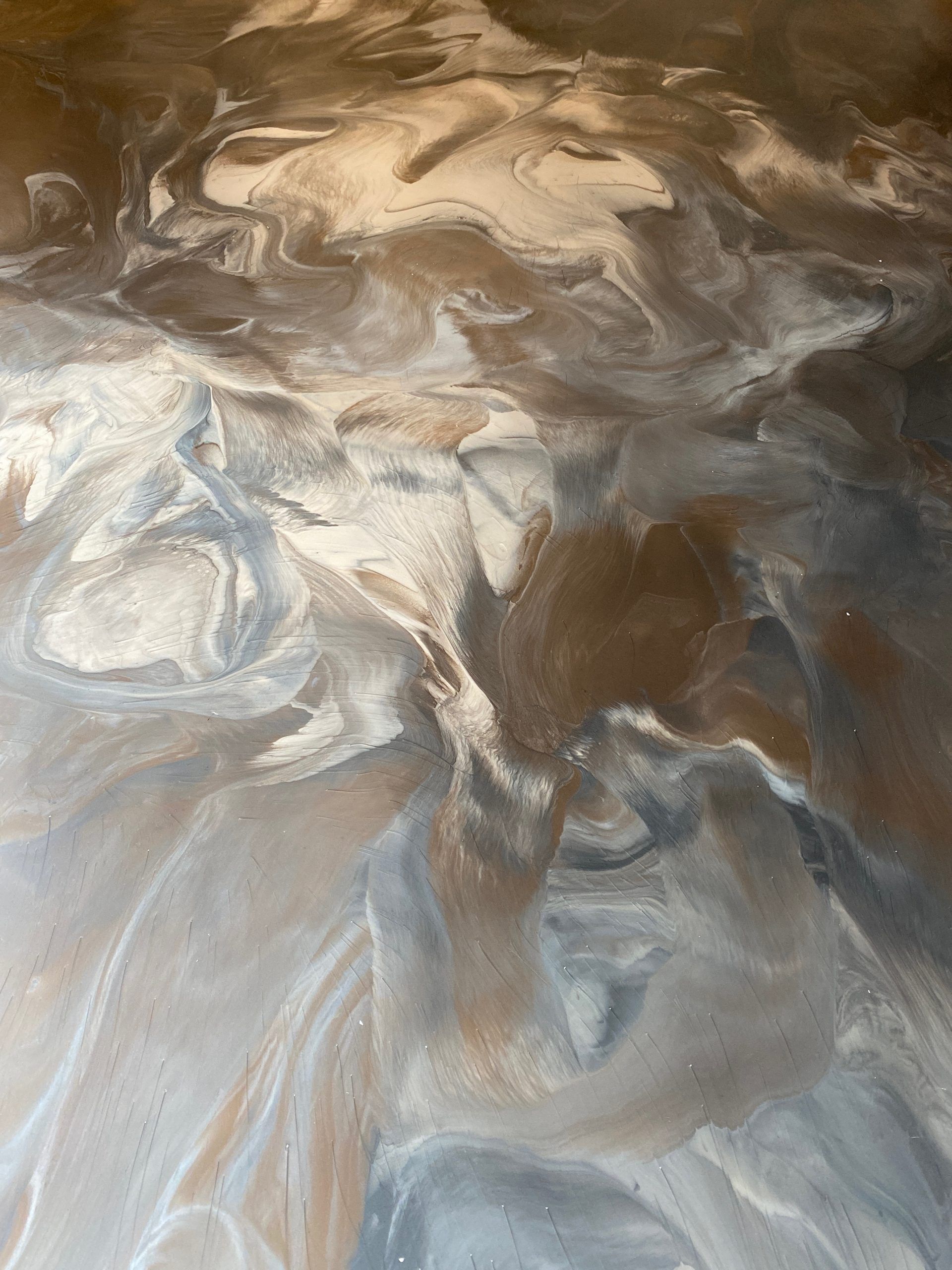 Abstract swirls of brown, cream, and gray paint resembling clouds or marble.