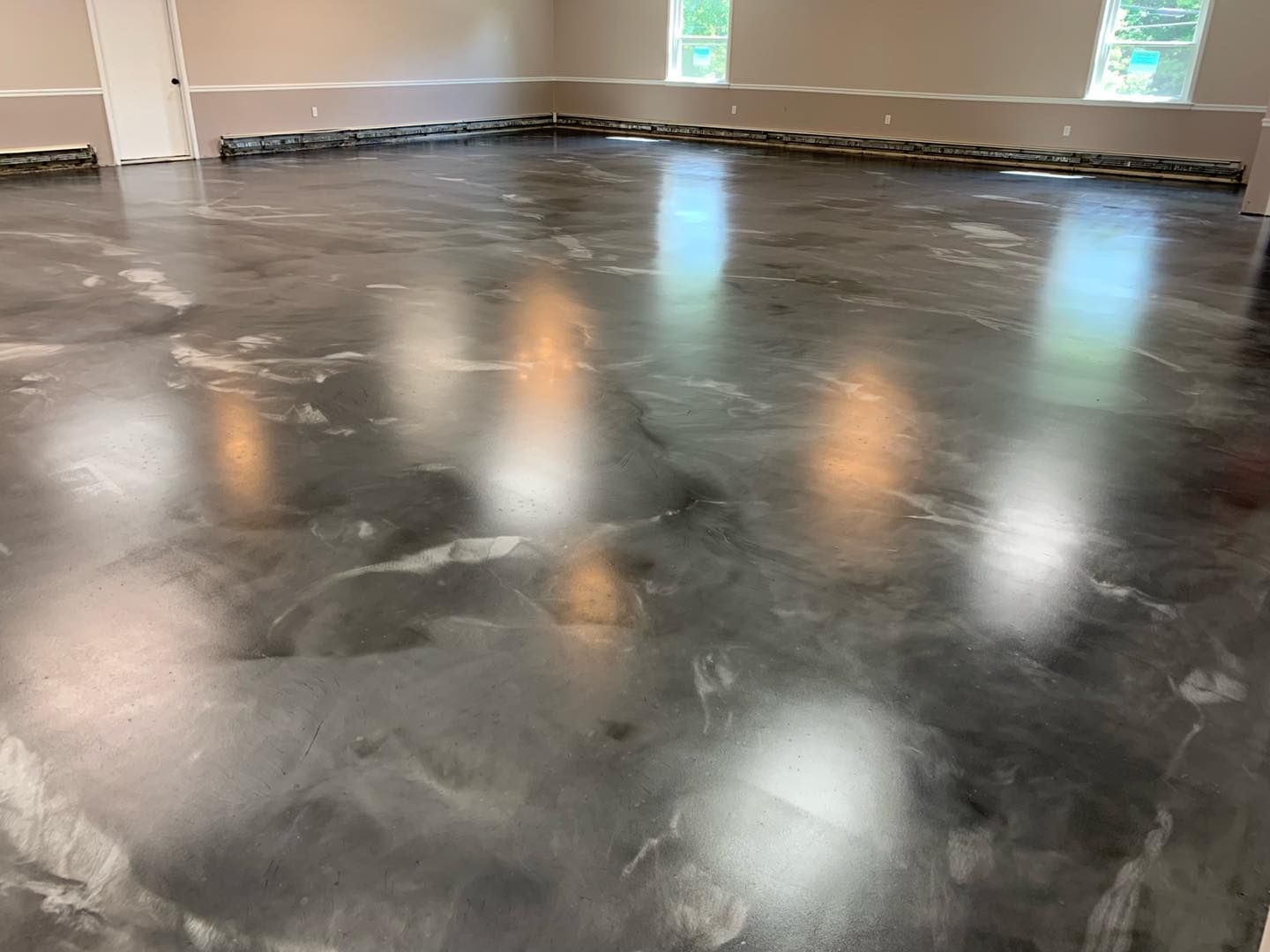 Smooth black epoxy floor with cloudy white swirls in a bright empty room