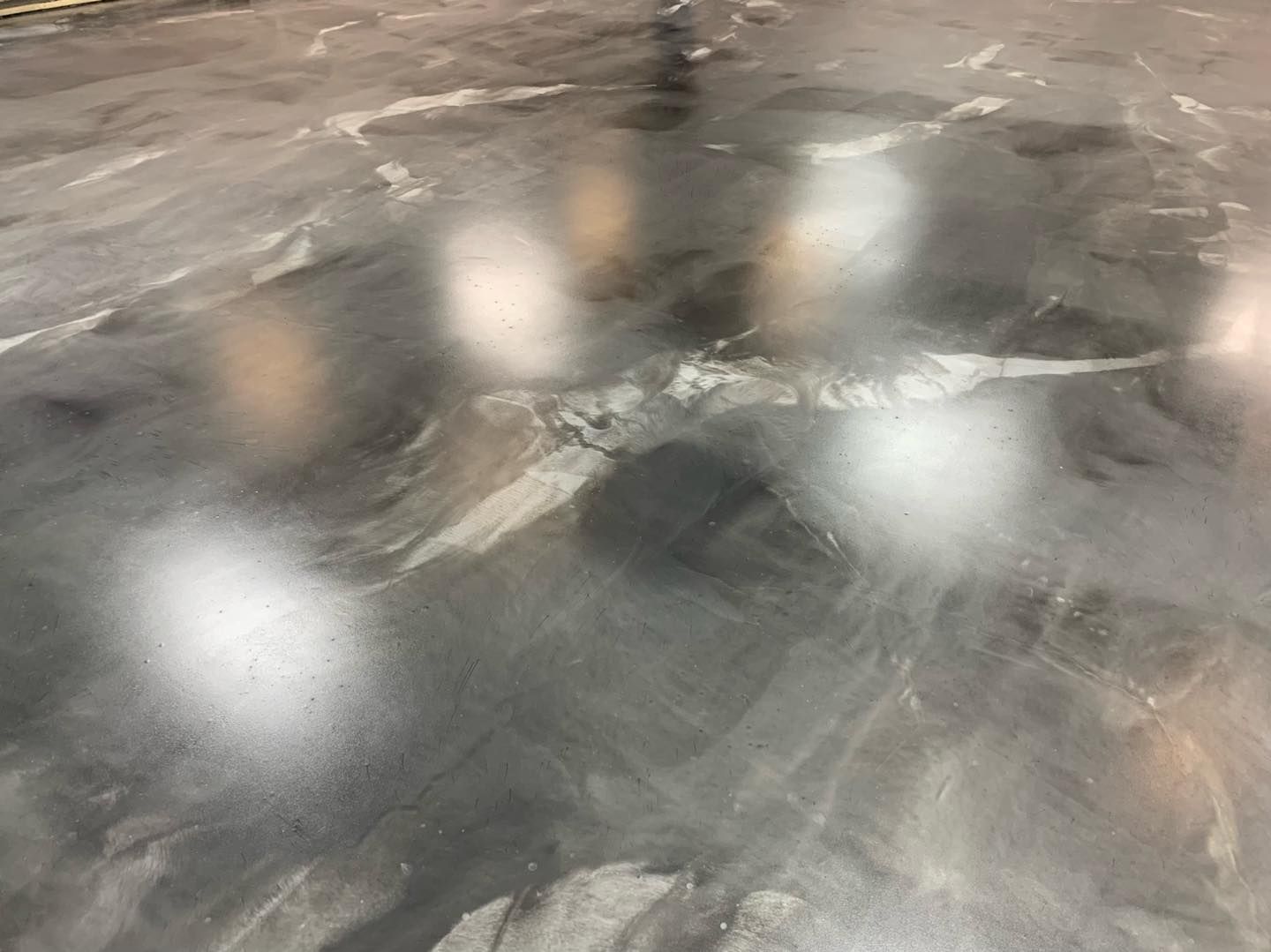 Shiny gray marbled concrete floor with bright reflected light spots