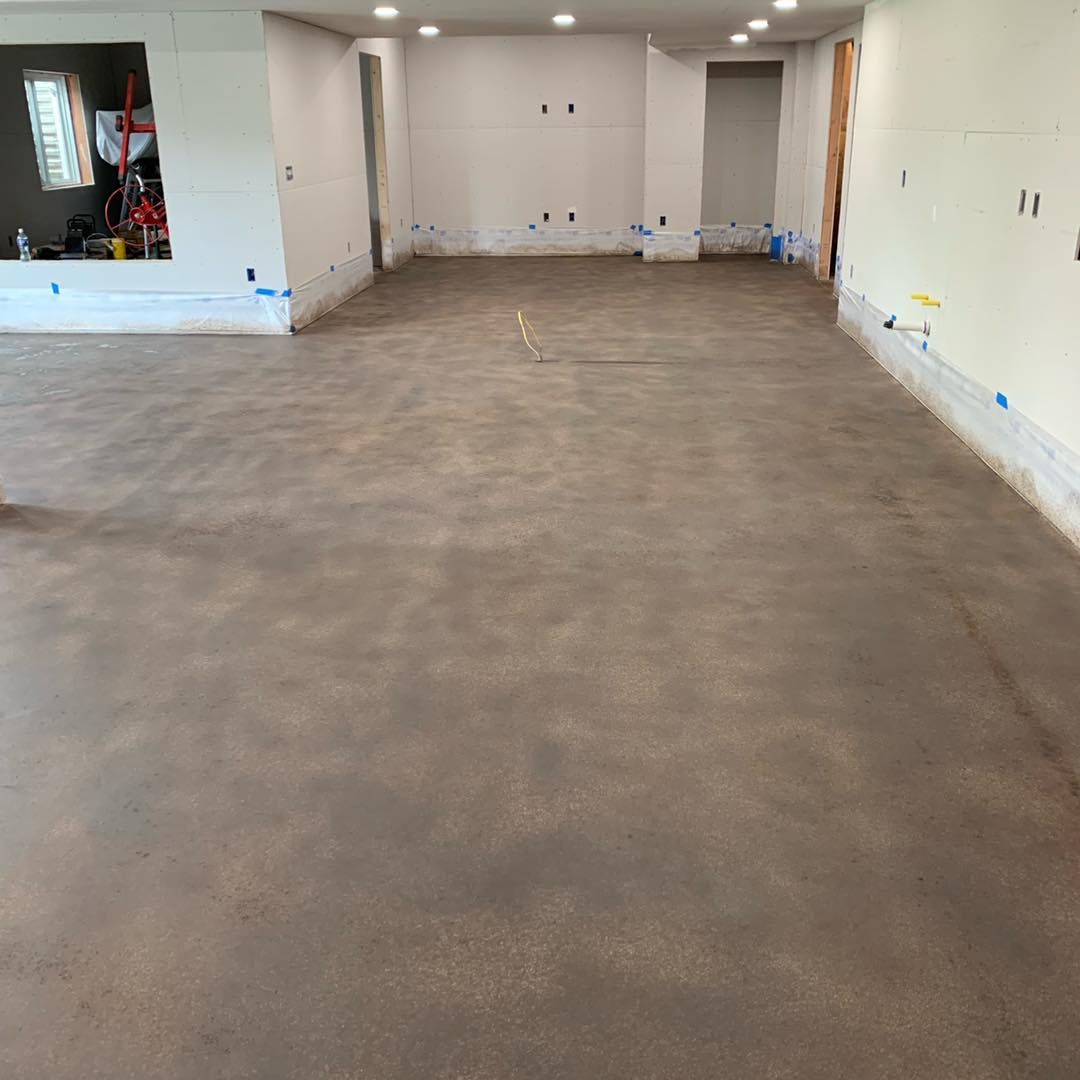 Empty unfinished room with gray concrete floor, white walls, and recessed ceiling lights.