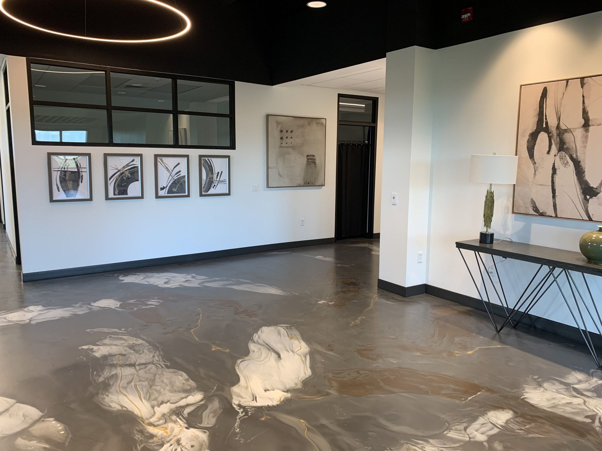 Modern art gallery with framed sketches, abstract floor art, and a large circular ceiling light