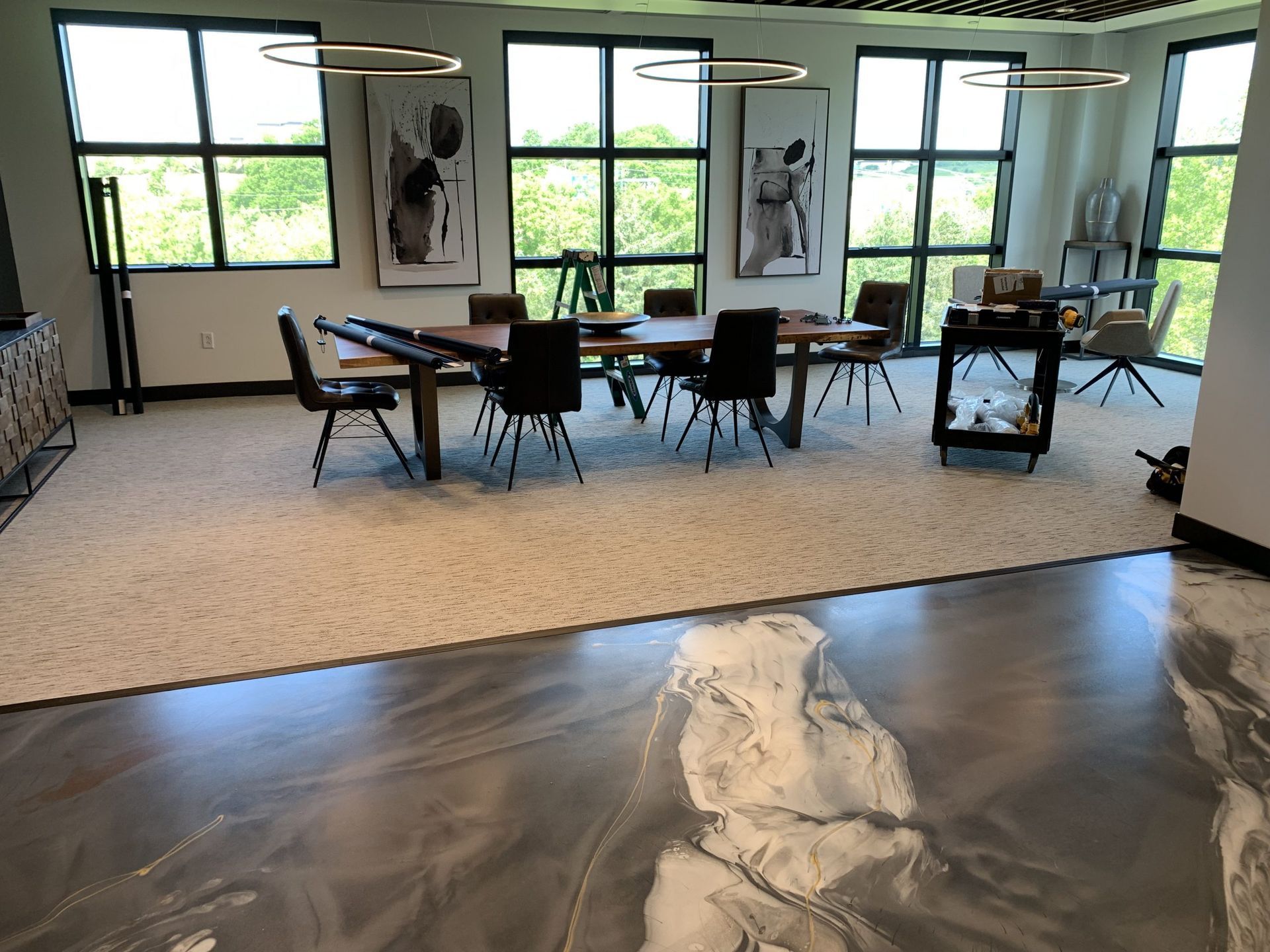 Modern conference room with large windows, black chairs, table, and a textured rug with an abstract floor design