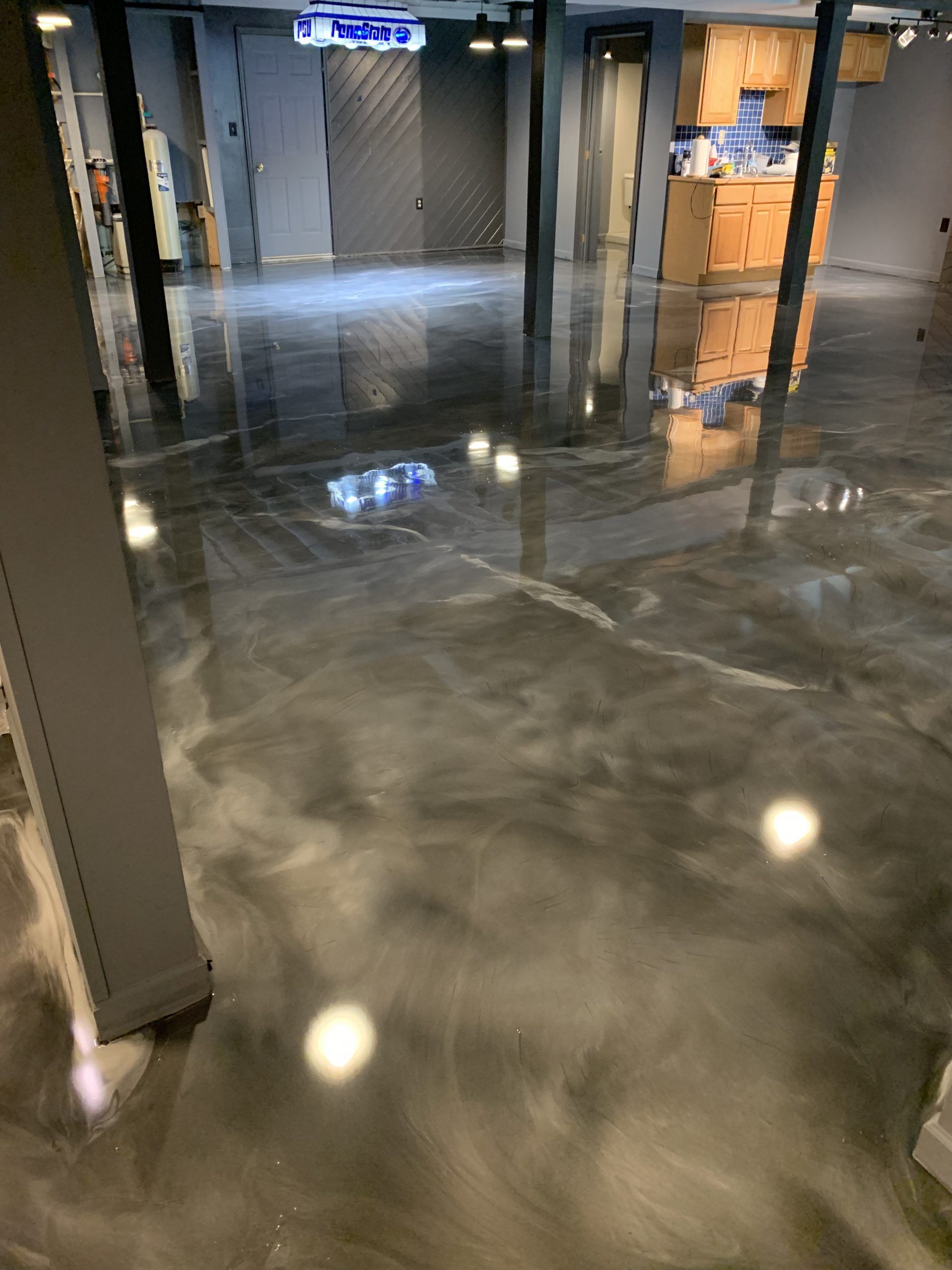 Flooded indoor hallway with reflective water and overhead lights, near office doors and cabinets