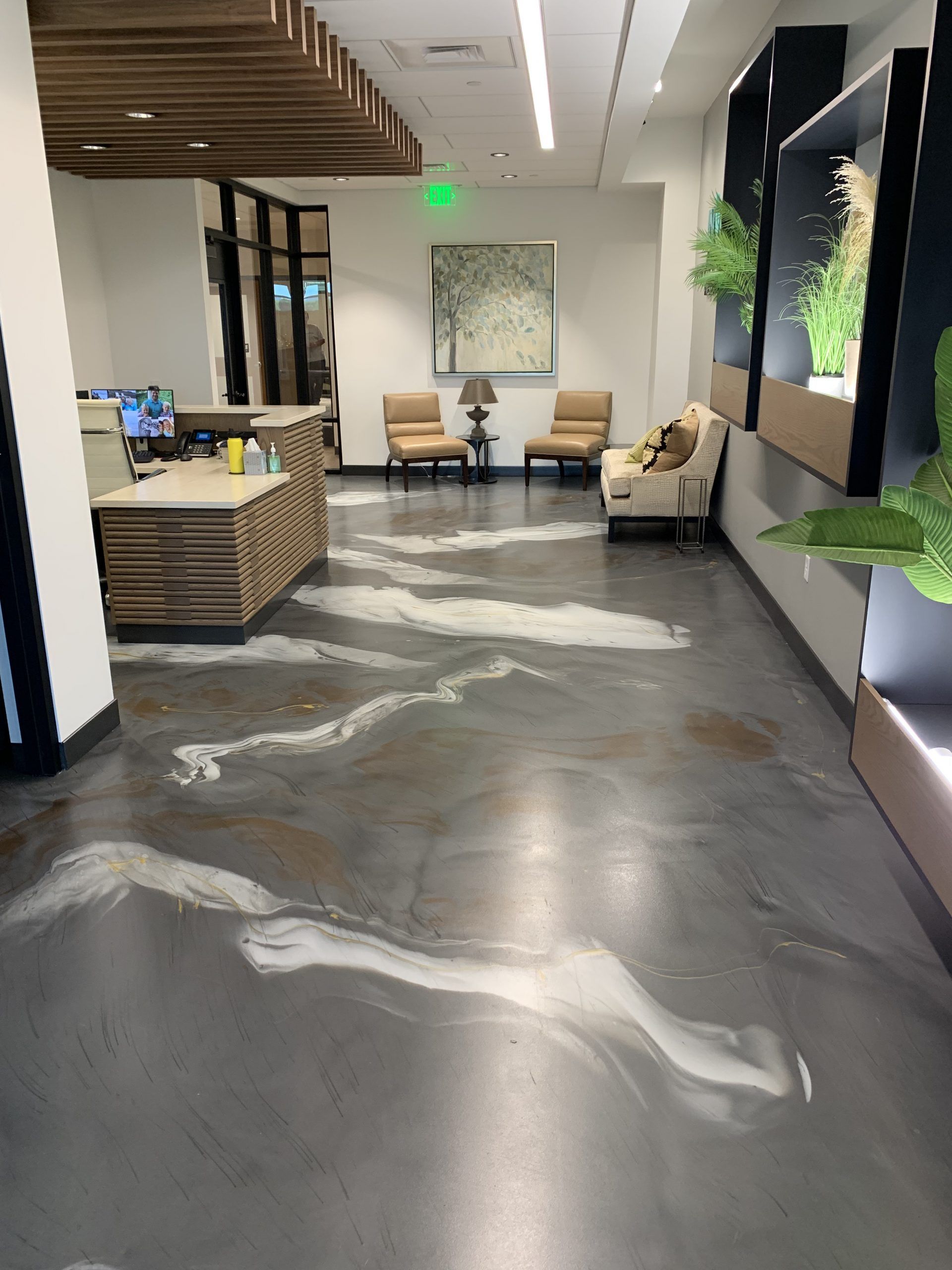 Modern office lobby with gray abstract floor, white chairs, reception desk, and large wall art