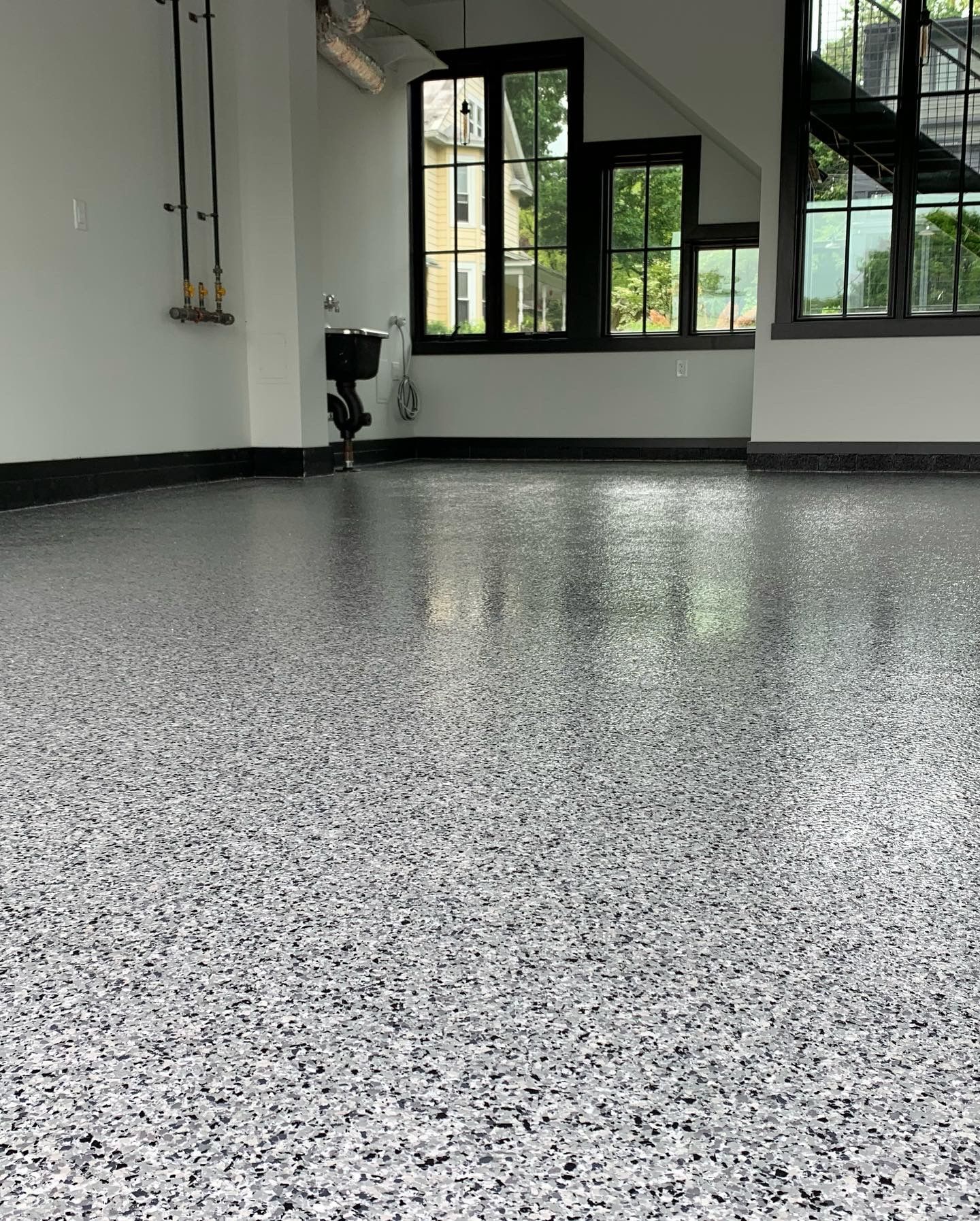 Empty speckled epoxy floor in a modern room with black-framed windows and gray walls