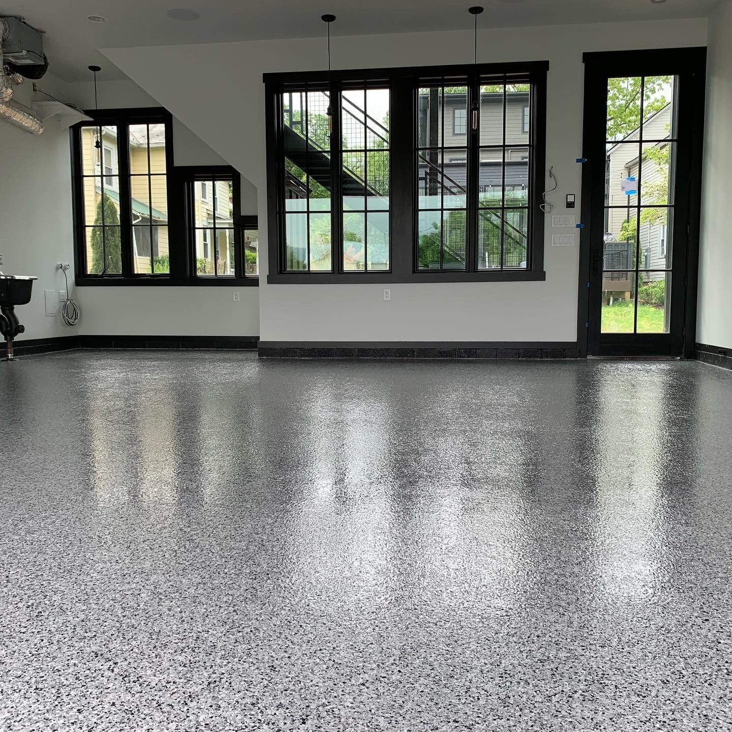 Empty modern room with black-framed windows and a speckled gray floor