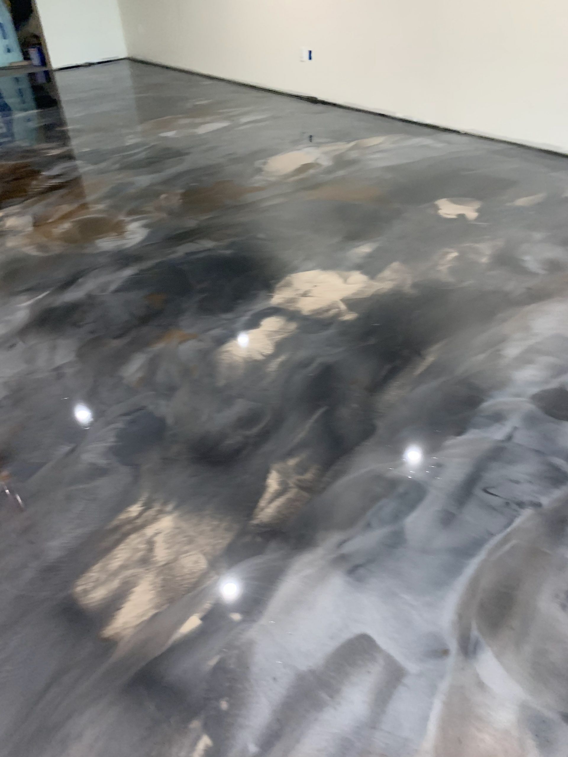 Partially finished concrete floor with dark gray and white swirls in an empty room