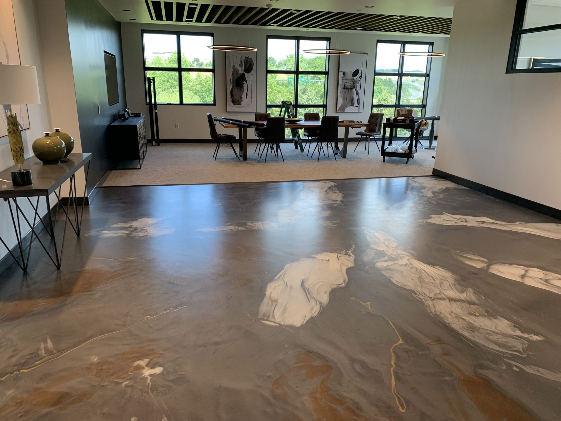 Empty room with large windows and mural-covered floor, featuring a glossy abstract floor installation