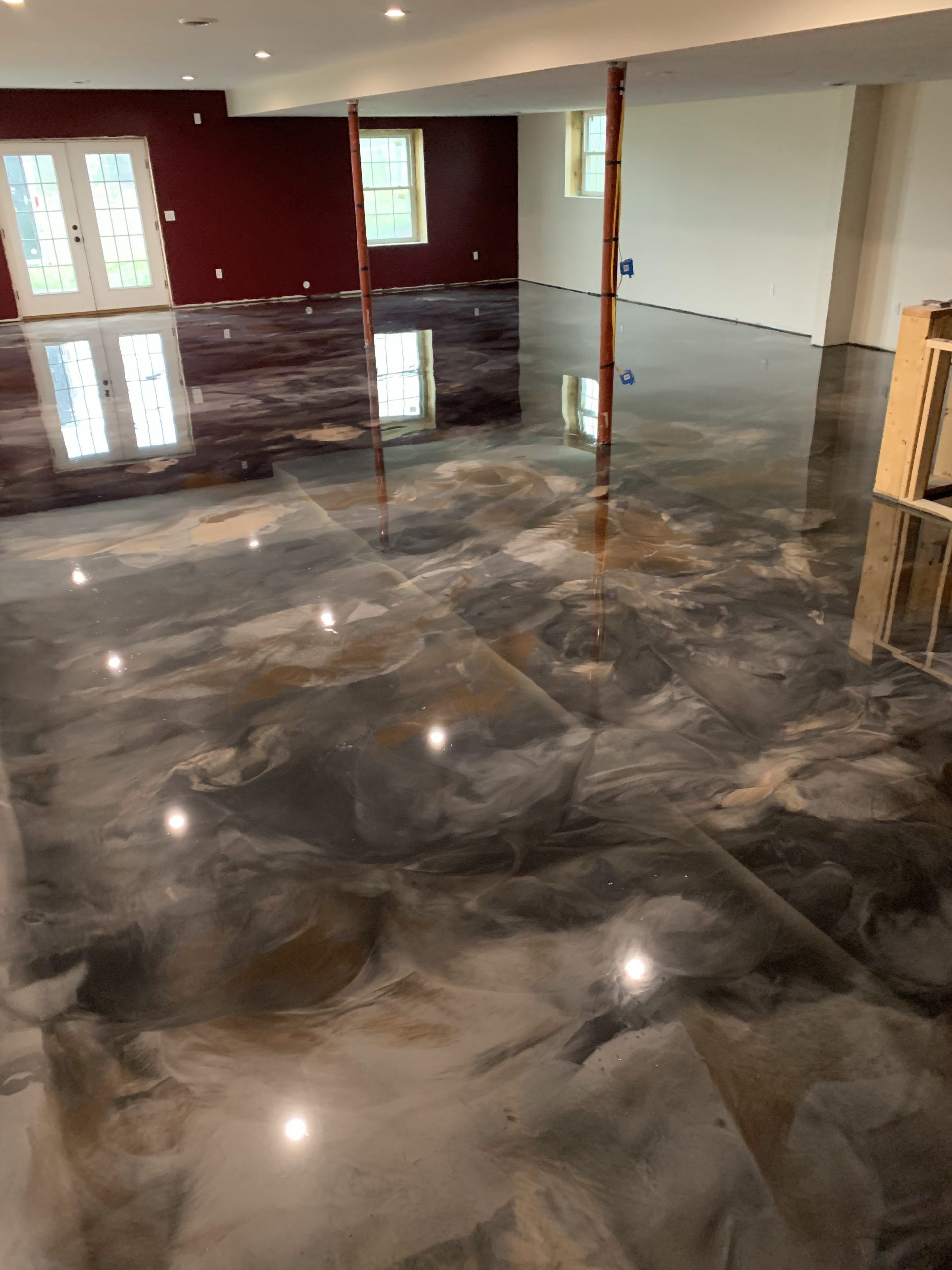 Shiny marbled concrete floor in an empty room with red walls and windows, reflecting ceiling lights