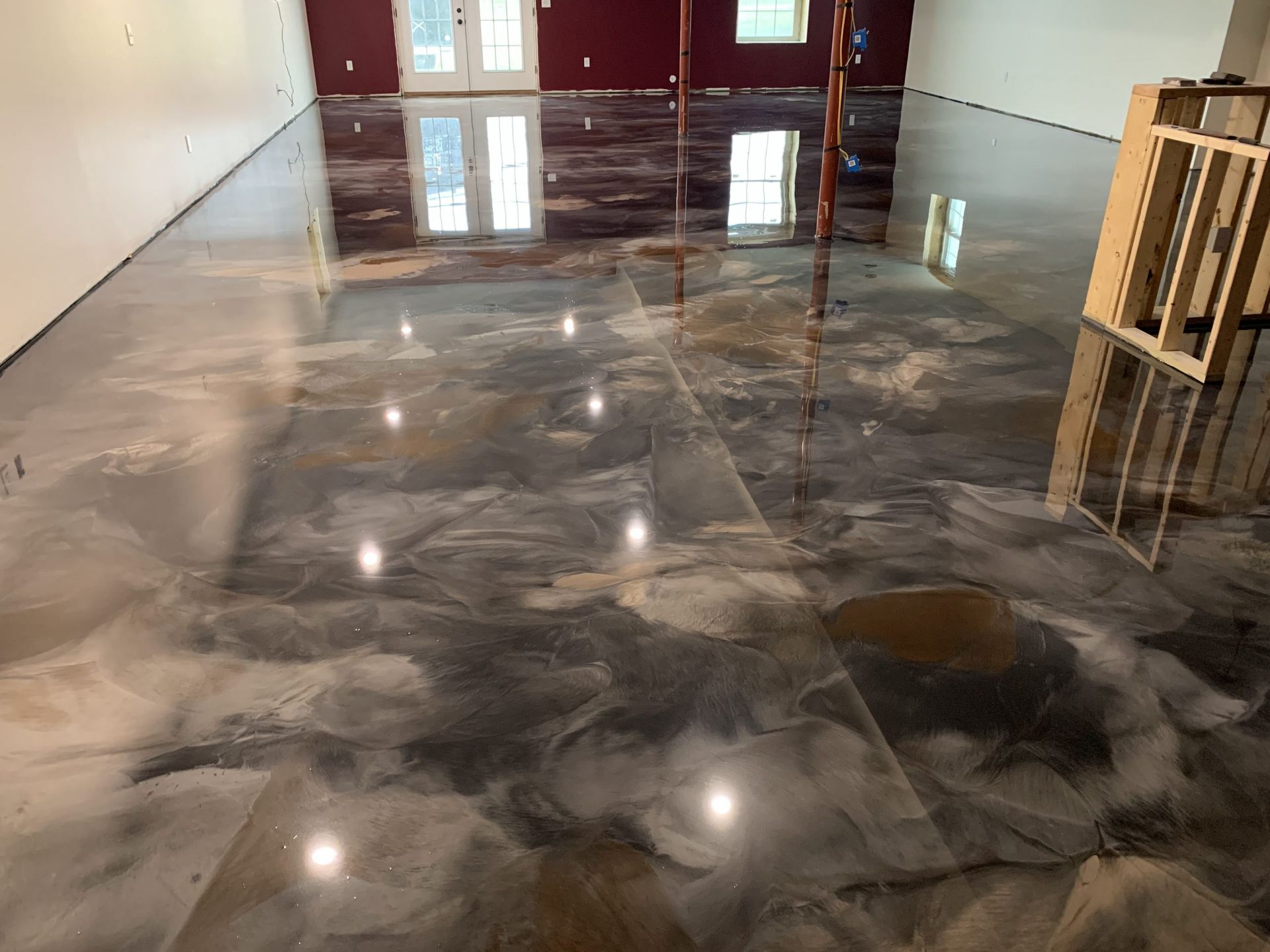 Glossy gray marble floor in a room under construction with windows and unfinished walls