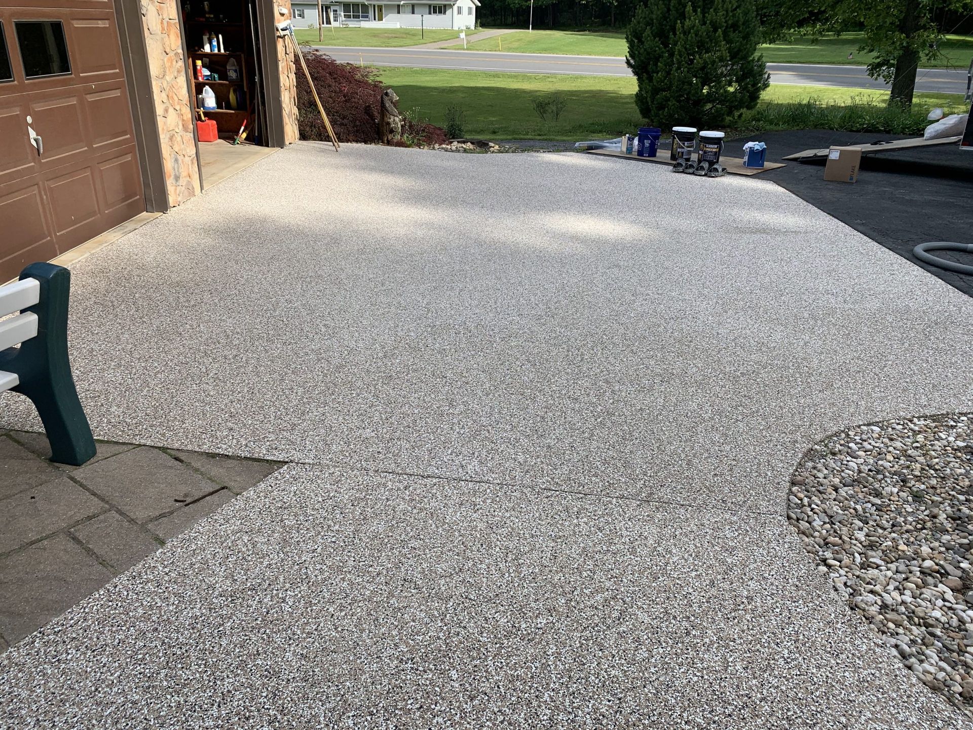 Freshly laid white gravel driveway beside a garage and walkway, with a street and lawn in the background