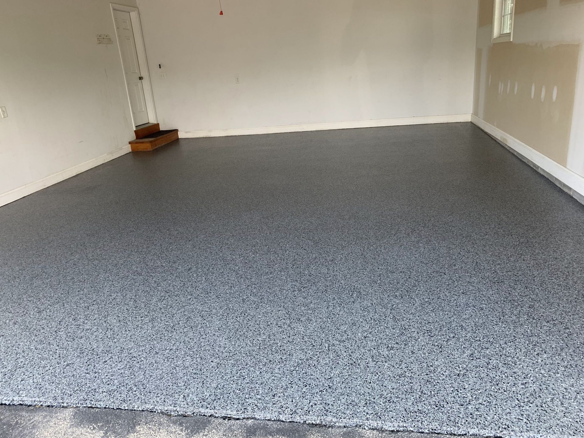 Empty garage with gray speckled floor and white walls