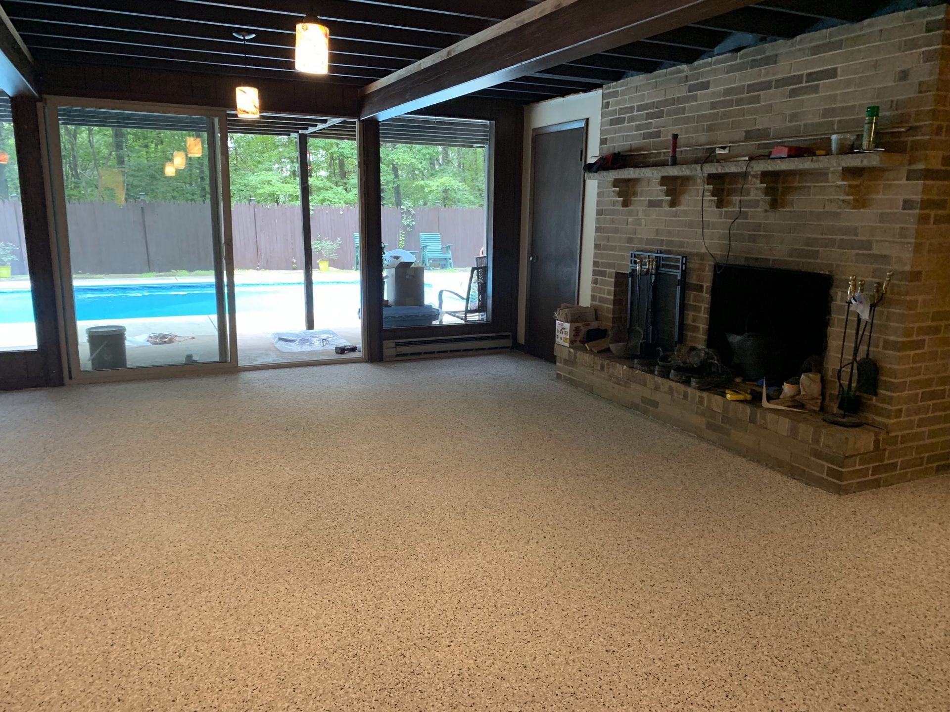 Spacious living room with brick fireplace and sliding glass doors opening to a backyard pool.