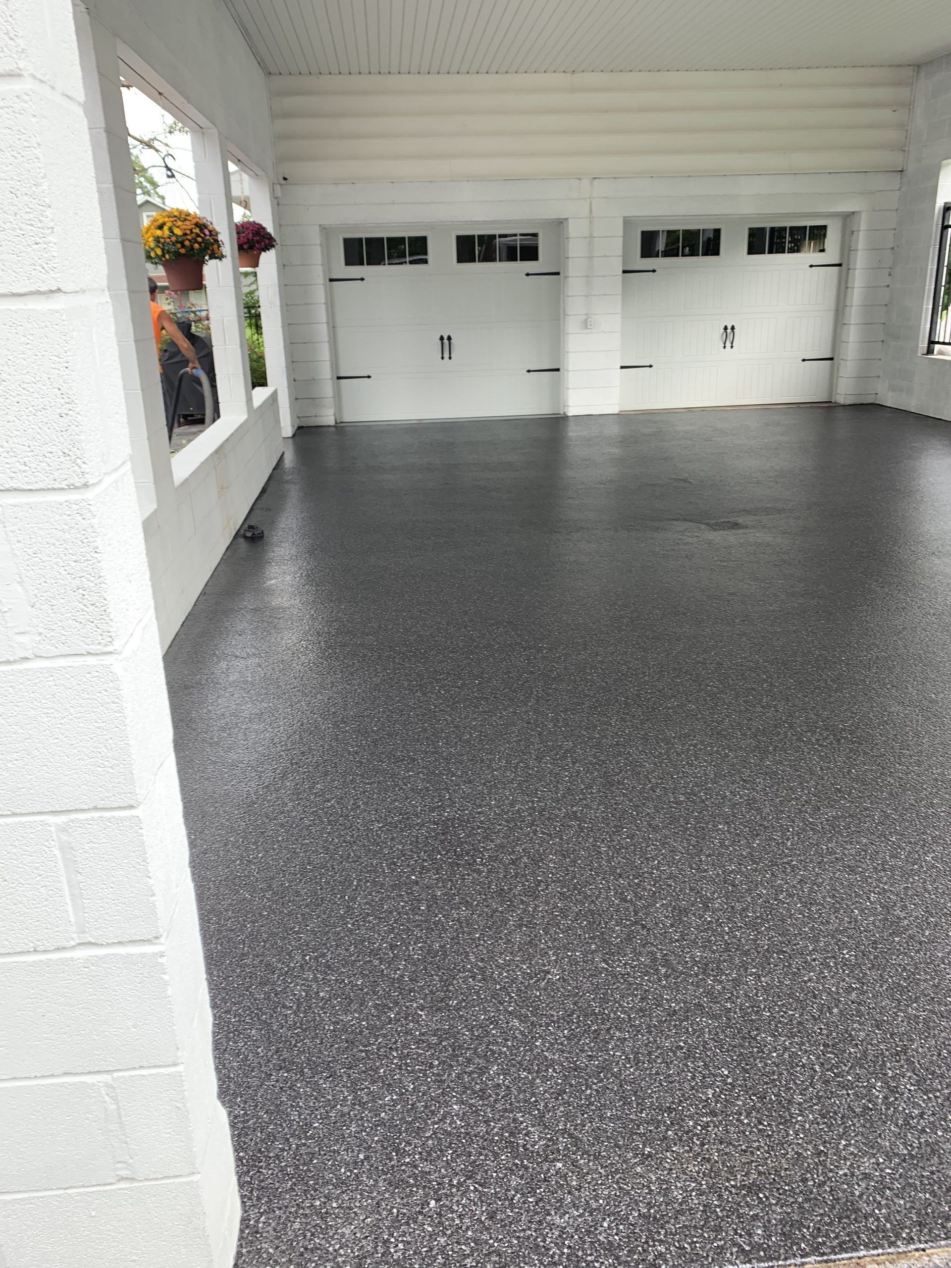 White house garage with two closed doors and a dark speckled floor, viewed from the driveway