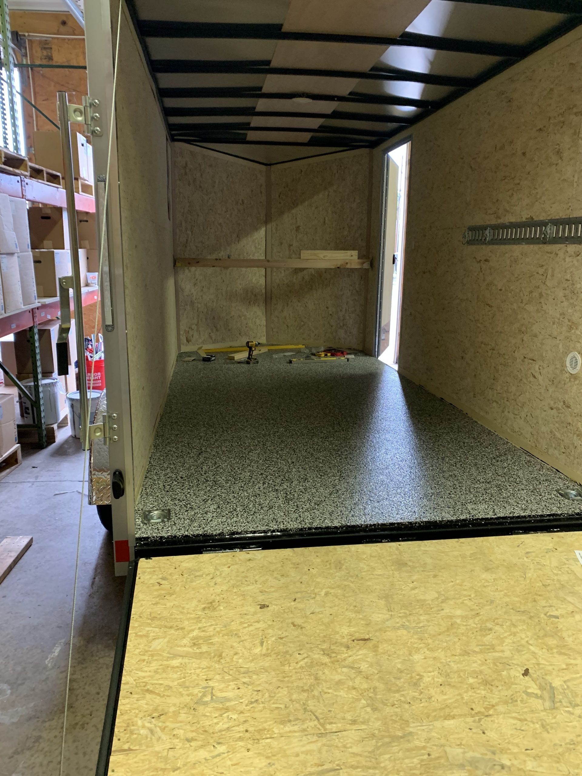 Interior of a box truck with a black-speckled floor and tan walls, viewed from the open rear.