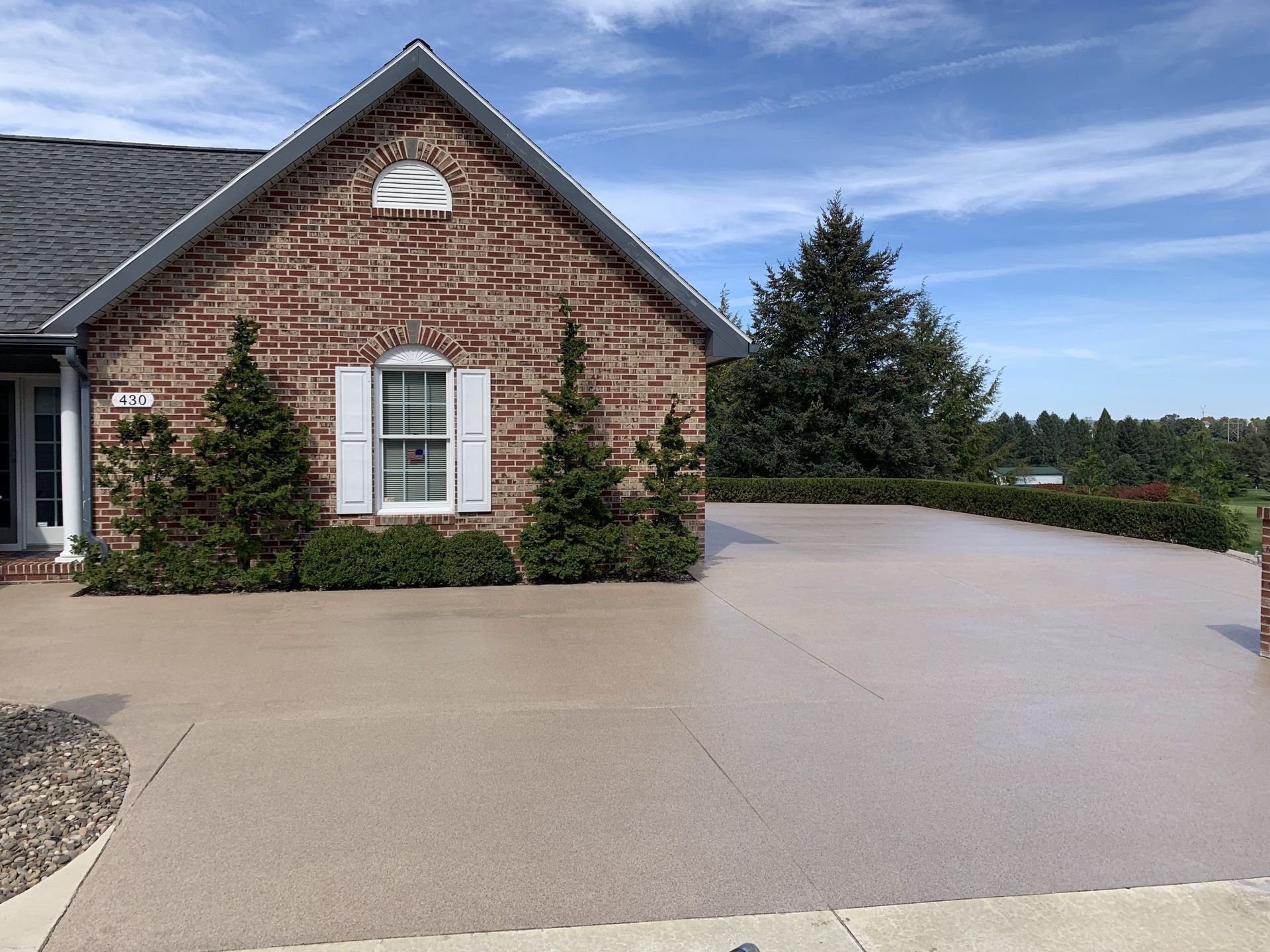 Brick house with a large stamped concrete driveway and landscaped front yard