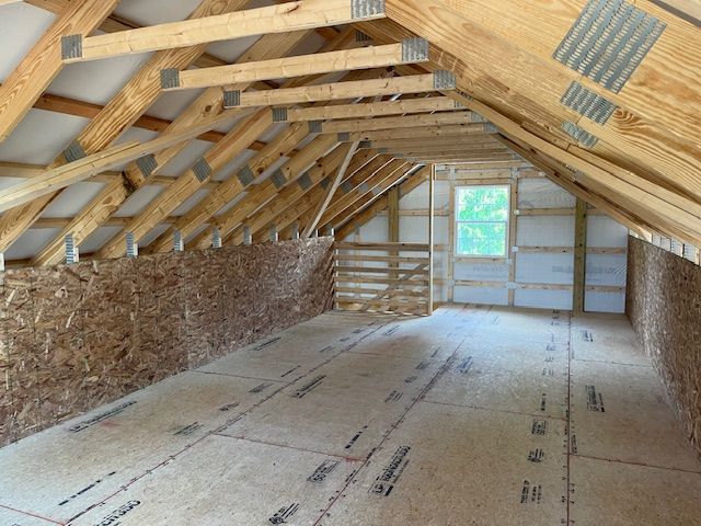 An attic under construction with wooden beams and a window