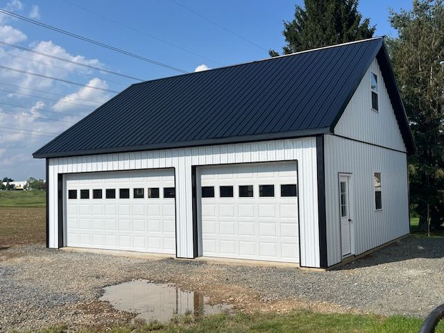 A white garage with a black roof and white garage doors