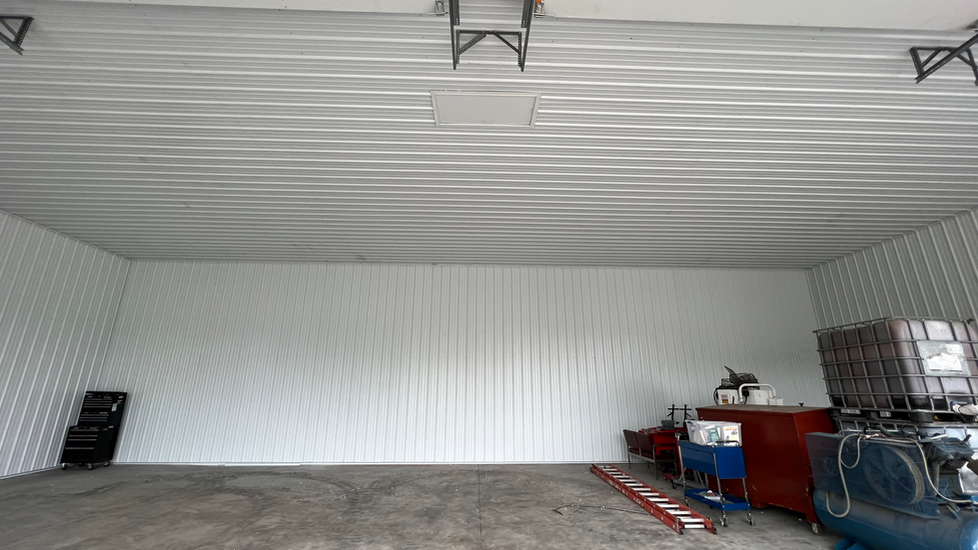 A large empty garage with white walls and a ladder.