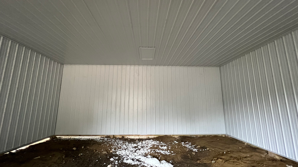 An empty garage with white walls and a muddy floor.