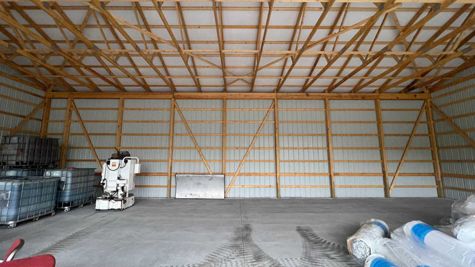 A large warehouse with a wooden roof and a motorcycle parked inside of it.