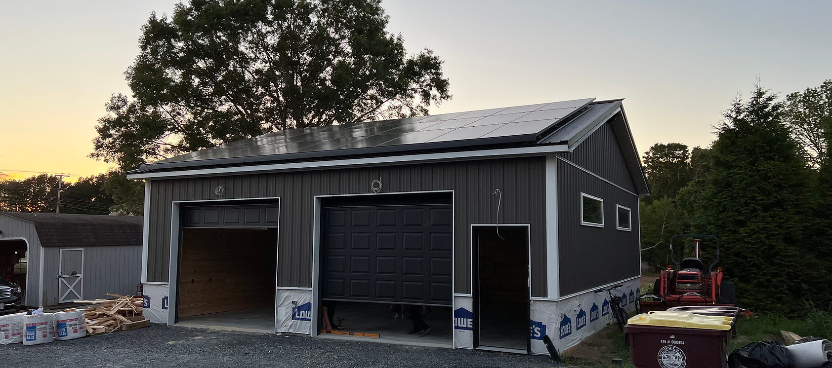 A garage is being built with a solar panel on the roof.