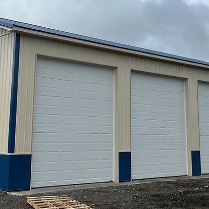 A building with three garage doors and a pallet in front of it.