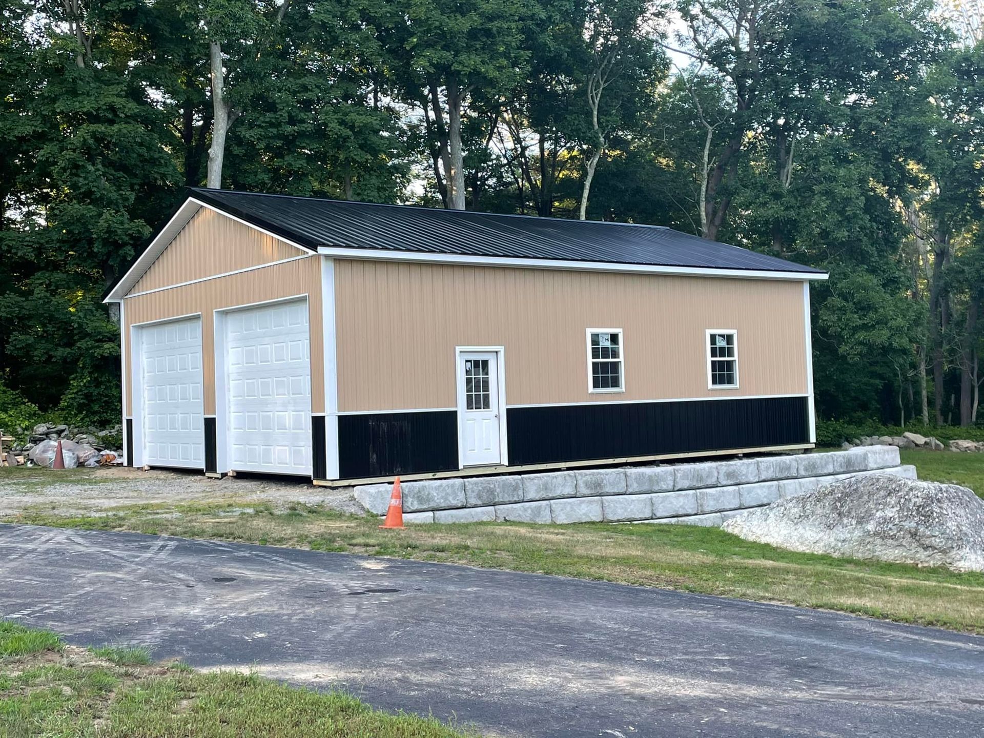 A garage with two garage doors and a black roof