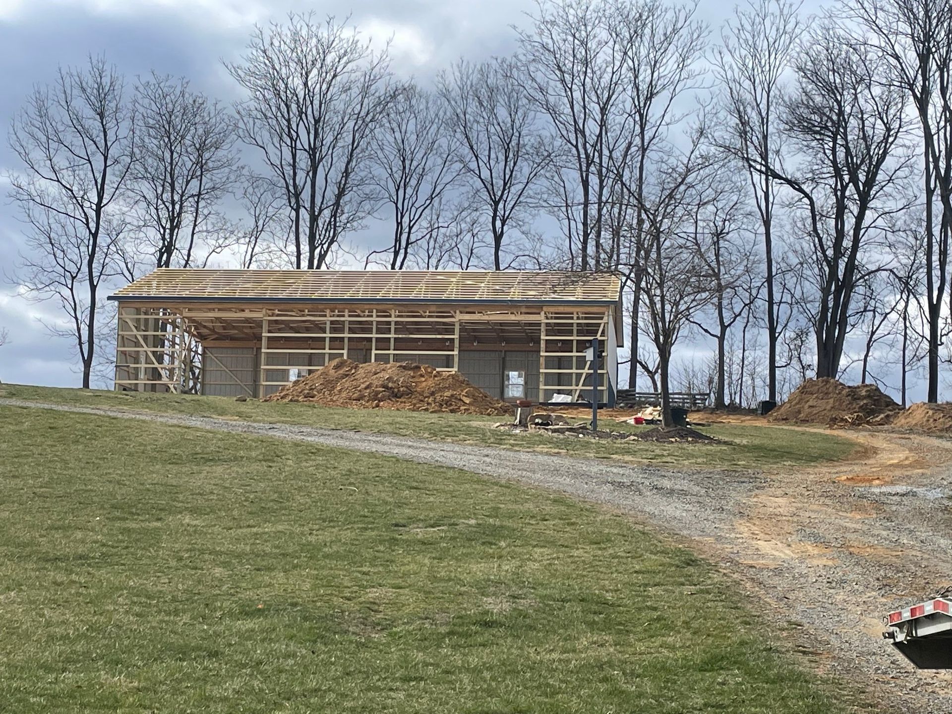A barn is being built in the middle of a grassy field.