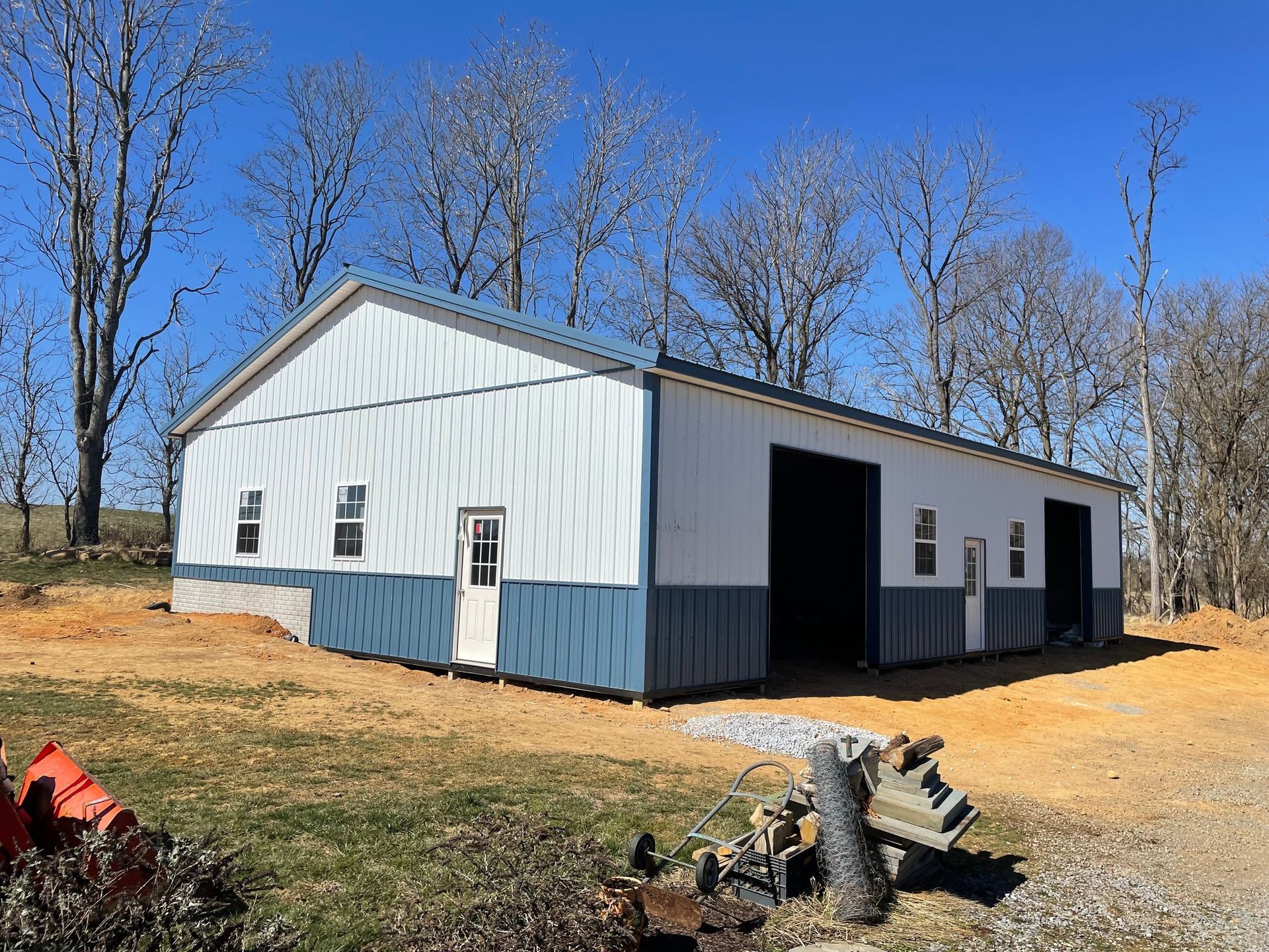 A large white and blue building with a wheelbarrow in front of it.