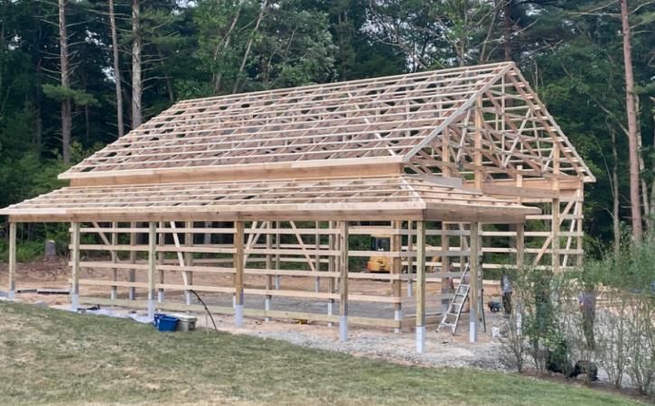 A large wooden structure is being built in the middle of a field.