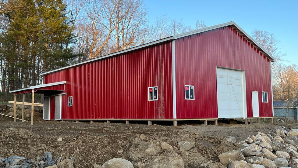 A large red barn is sitting in the middle of a dirt field.