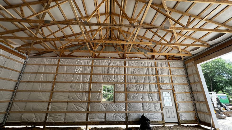 The inside of a garage under construction with wooden beams and insulation.