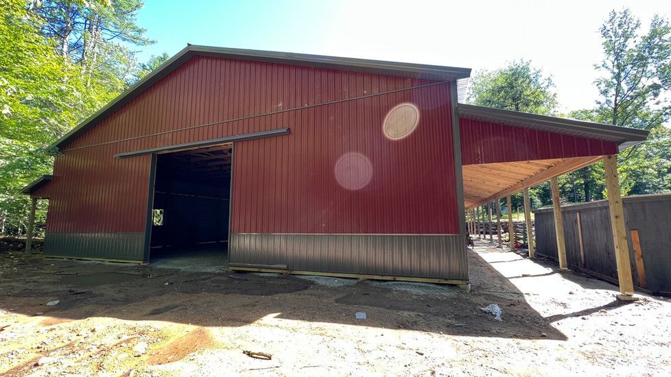 A large red barn with a carport attached to it.