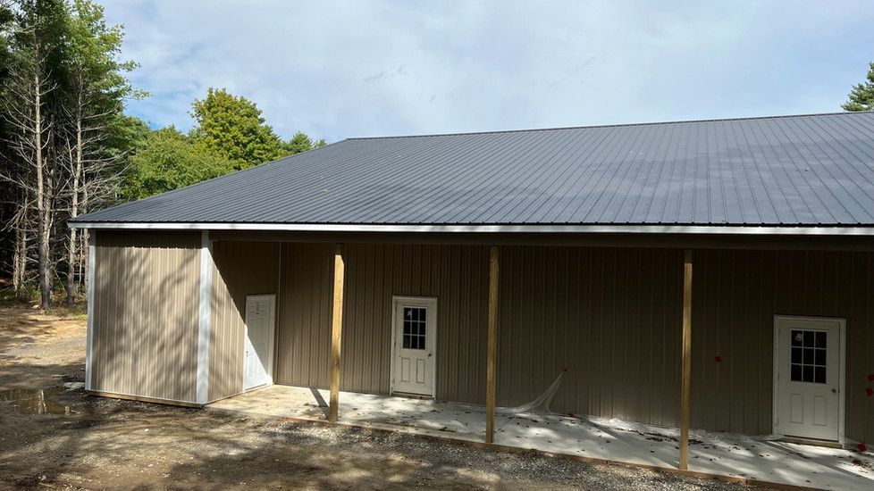 A large brown building with a black roof and a porch.